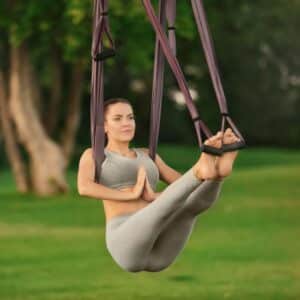 Une femme qui fait du yoga aérien en extérieur sous un arbre