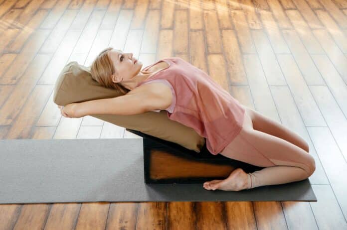 Une posture de yoga iyengar avec un accessoire